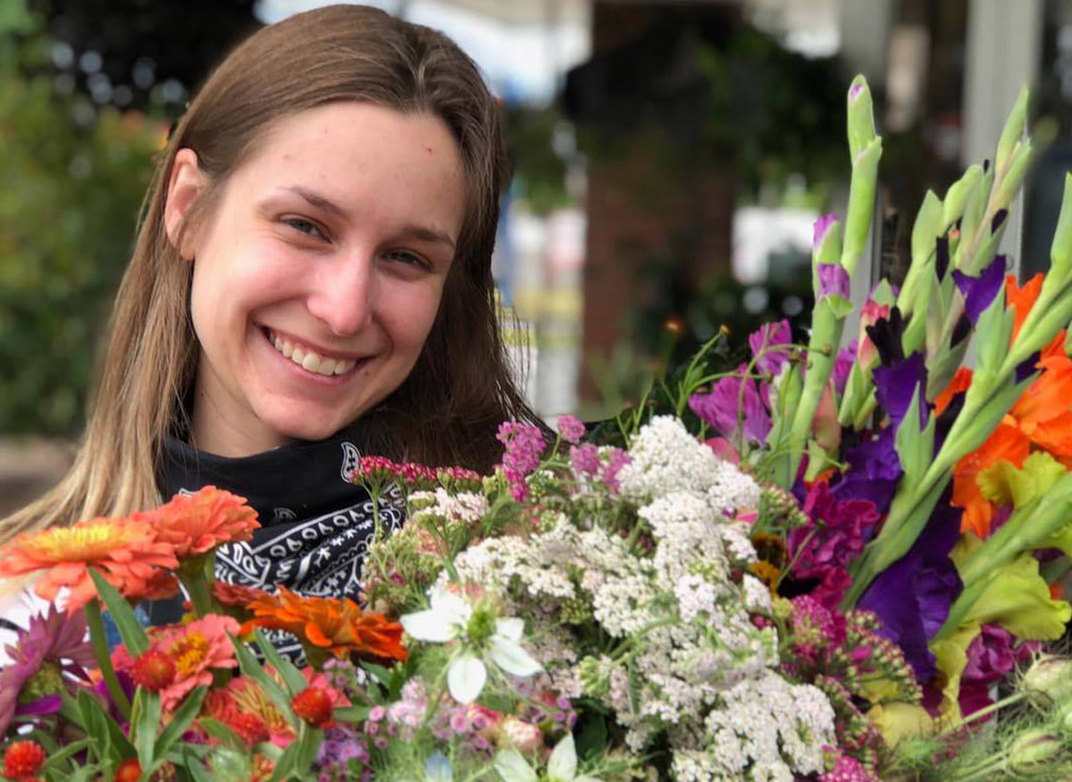 A Shirley's employee smiles while holding a large bouquet near our front desk